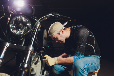 Man fixing bike. Confident young man repairing motorcycle near his garage.の写真素材