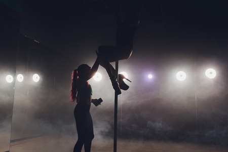Pretty pole fitness instructor assisting one of her students during class.の写真素材