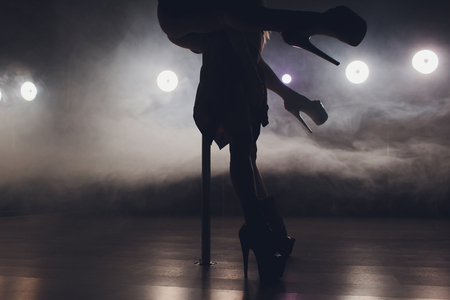young striptease dancer moving in high heels shoes on stage in strip night club, Pole dancingの写真素材