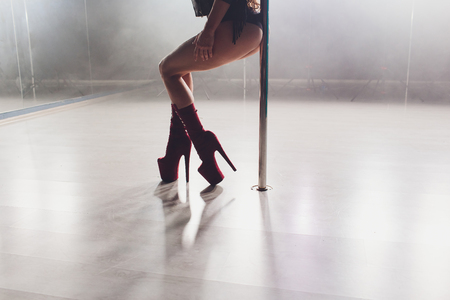 young striptease dancer moving in high heels shoes on stage in strip night club, Pole dancing