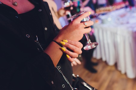Cocktail glass in womans hand with bar on back.の写真素材