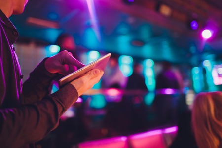 Event tuner controlling sound from tablet on the background of karaoke bar.の写真素材