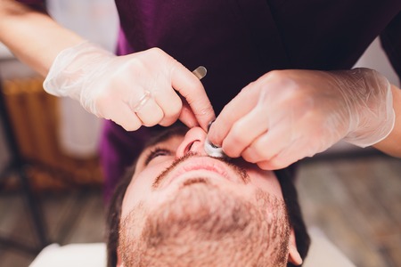 Hair removal. Mans face sugaring epilationsy ellow color, in cosmetology on the couch. hair removal inside the nose.の写真素材