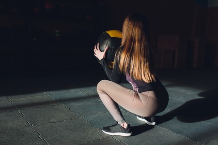 Beautiful young woman in fitness center doing pilates exercise with fitness ball. Healthy lifestyle concept.の写真素材