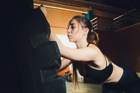 Fitness woman flipping wheel tire in gym. Fit female athlete working out with a huge tire. Back view. Sportswoman doing an strength exercise training.の写真素材
