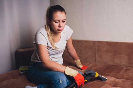 Tired woman having rest after cleaning home, lying on sofa in the living-room, copy space. Housekeeping and home cleaning concept.の写真素材