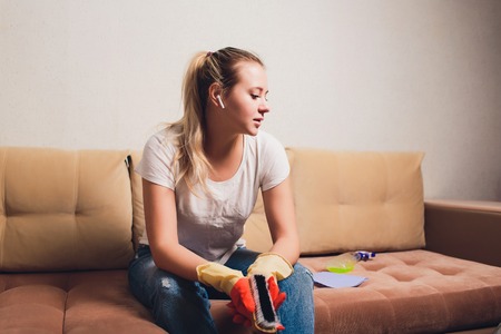 Tired woman having rest after cleaning home, lying on sofa in the living-room, copy space. Housekeeping and home cleaning concept.の写真素材