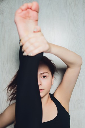 Top view of young attractive woman doing King Cobra pose, Raja bhudjangasana exercise with tattoo on her foot meaning Wild kitty , short red nails, feet with pedicure, closeup, closed eyes.の写真素材