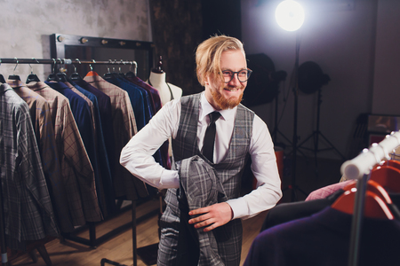 Young shopaholic man chousing jacket at boutique.の写真素材