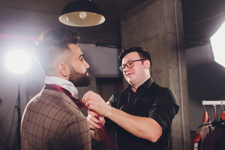 Mature professional Tailor taking measurements for sewing suit at tailors shop. Man with measuring tape busy. Exclusive Custom Made Cloth Concept.の写真素材