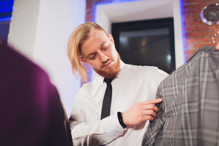 portrait of male client choosing classic jacket in the mall.の写真素材