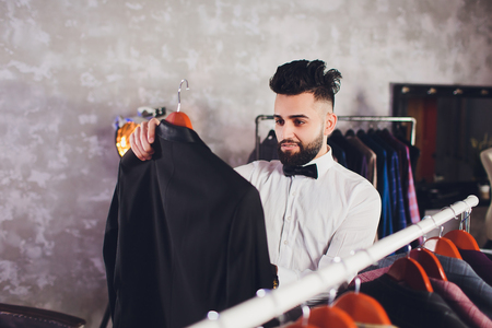 Positive guy customer looking jacket in men clothes store.の写真素材