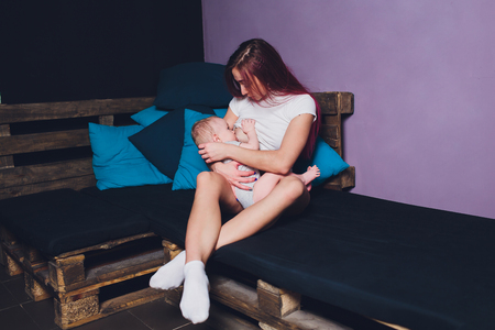 Mother breastfeeding baby in her arms at home. Beautiful mom Red hair breast feeding her newborn child. Young woman nursing and feeding baby. Concept of lactation infant.の写真素材
