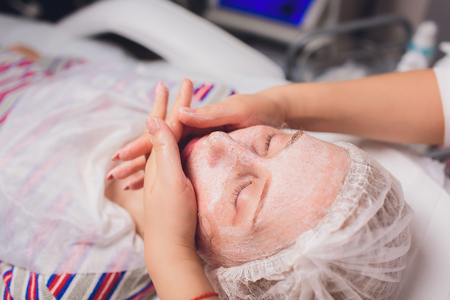 Beautiful young woman having a facial cosmetic mask at spa salon. Girl is having cosmetic treatment.の写真素材
