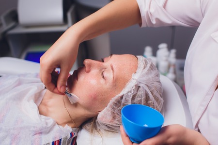 Beautiful young woman having a facial cosmetic mask at spa salon. Girl is having cosmetic treatment.の写真素材