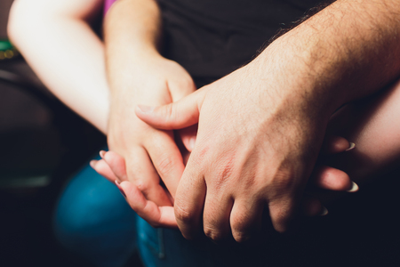 Close up male and female holding hands over table.の写真素材