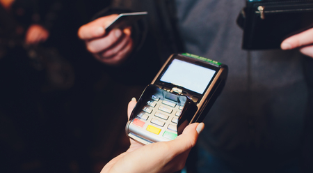 Man paying with NFC technology on mobile phone in shopping mall, point of view, close-up.の写真素材