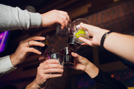 Hands of people with glasses of whiskey or wine, celebrating and toasting in honor of the wedding or other celebration.の写真素材