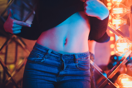 Young athletic woman belly on blue background. Front view. Close-up.の写真素材