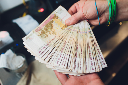 A close up photo of a Caucasian male hand holding a 100 Russian ruble note.の写真素材