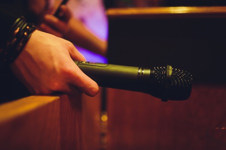 Close up male hand holding microphone. in the interior of the bar.の写真素材