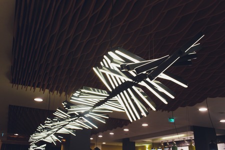 Silver and copper metal curved ribbon chandelier closeup. Modern metal lampshade. Black and white abstract textured background. Abstract chaotic pattern. Futuristic backdrop. Interior decoration.の写真素材