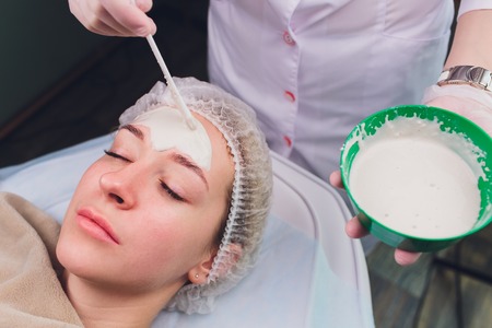 Beautiful woman having a facial cosmetic scrub treatment from professional dermatologist at wellness spa. Anti-aging, facial skin care and luxury lifestyle concept.の写真素材