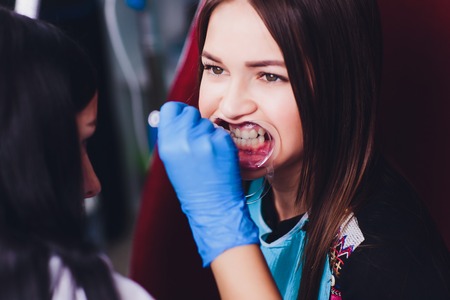 Dentist curing female patient Woman teeth examined at dentists teeth whitening. stomatology office...