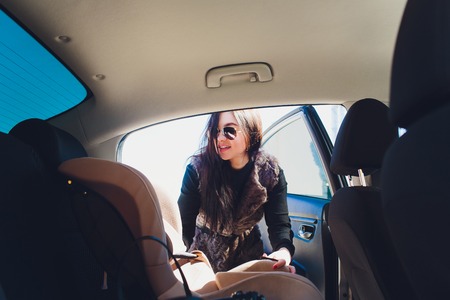 Woman with baby safety seat placing it in the car.の写真素材