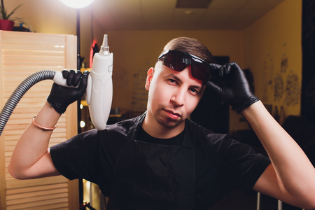 Cosmetologist professional tattoo removal laser in salon.の写真素材
