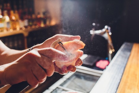 The bartender cuts orange peel over a cocktail. Close-up.の写真素材