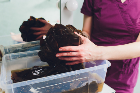 Spa treatment with algae. Woman on seaweed wraps at a spa salon. Firming procedure.の写真素材