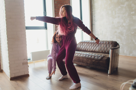 Concept pajama party. Girlfriends of sister fight pillows on bed morning, sun shines in window.の写真素材