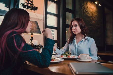 LGBT Cheerful female friends chatting in cafe. Two beautiful young women gossiping and drinking coffee. Friendship concept.の写真素材