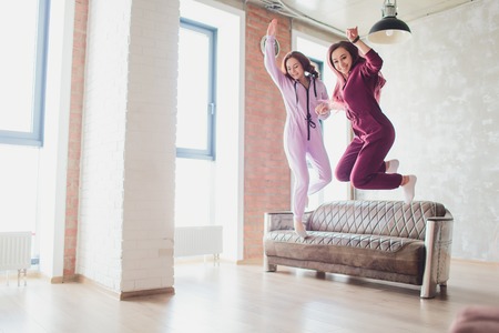 Professional two female athletes are sitting in yoga position together. They are touching their arms...