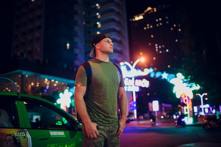 beautiful man brunet on a background of night illumination in asia.の写真素材