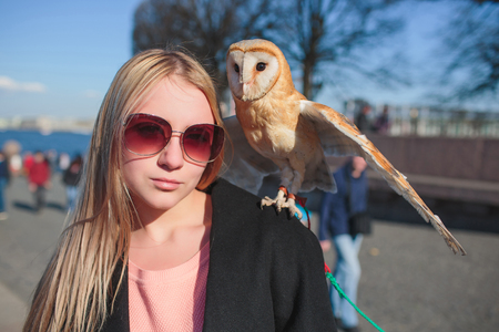 Beautiful woman with an owl on arm. Blonde with long hair in nature holding a owl. Romantic delicate image of a girl.の写真素材