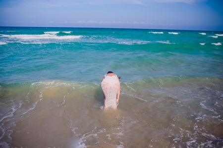 Young woman in white dress walking on tropical beautiful beach.の写真素材