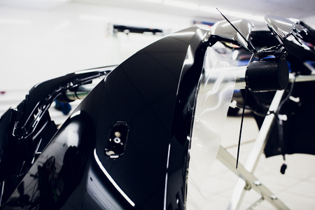 Worker hands installs car paint protection film wrap bumperの写真素材