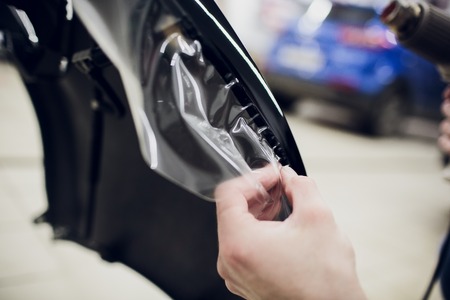 Worker hands installs car paint protection film wrap bumperの写真素材