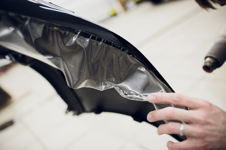 Worker hands installs car paint protection film wrap bumperの写真素材