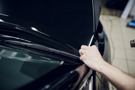 Worker hands installs car paint protection film wrap hoodの写真素材