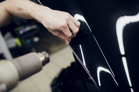 Worker hands installs car paint protection film wrap hoodの写真素材