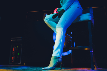 The female student is holding the black wireless microphone in the left hand and do the public speaking with blurred background.の写真素材