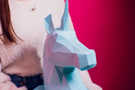 Fashion kid. Designer collection. White big unicorn origami made paper. Girl in beautiful pink dress. Studio shot.の写真素材