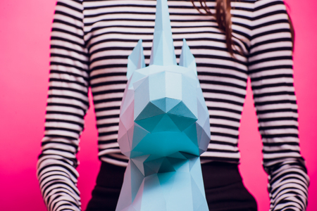 Fashion kid. Designer collection. White big unicorn origami made paper. Girl in beautiful pink dress. Studio shot.の写真素材