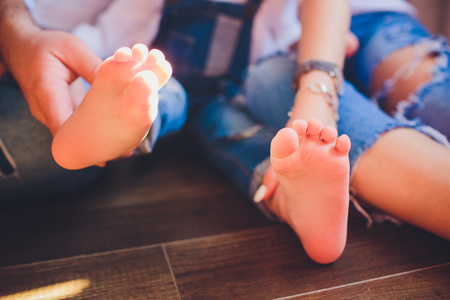 Adults parents hands holding little baby feet