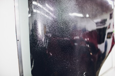 Applying tinting foil on car window in garageの写真素材