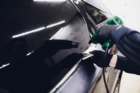 Applying tinting foil on car window in garageの写真素材