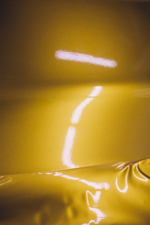 Car wrapping specialist putting vinyl foil or film on car wrapping protective film yacht, boat, ship, car, mobile home. yellow gold film hand pullsの写真素材